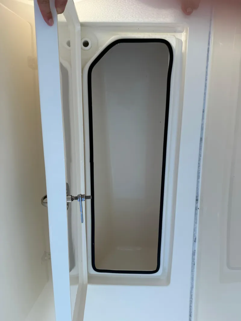 Slide: The Image of 2023 Cobia 350 Center Console storage compartment with open door. - 28