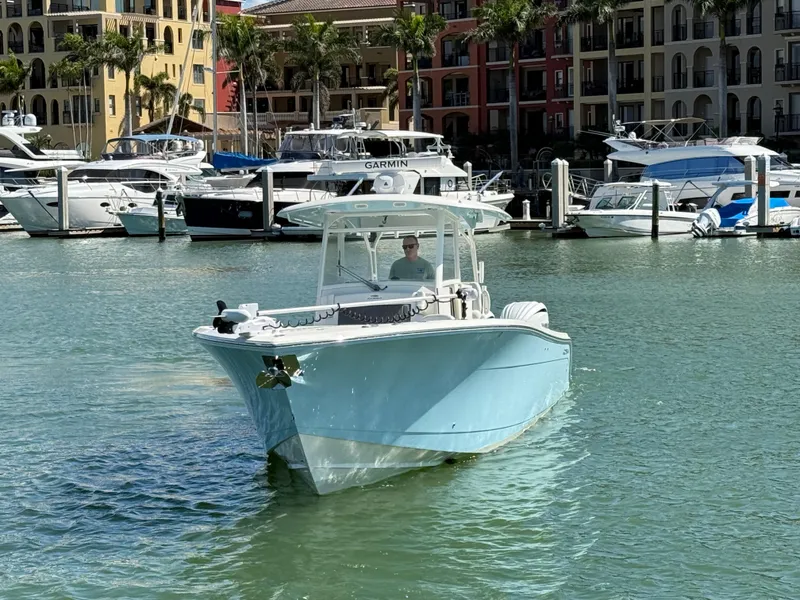 Slide: The Image of 2023 Cobia 350 Center Console boat cruising in a marina with docked yachts. - 3