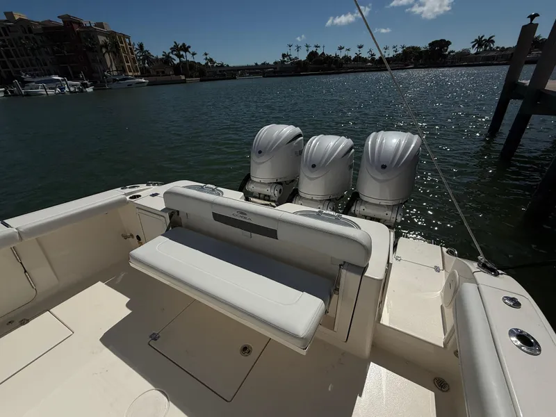 Slide: The Image of 2023 Cobia 350 Center Console boat with triple engines, docked by a scenic waterfront. - 31
