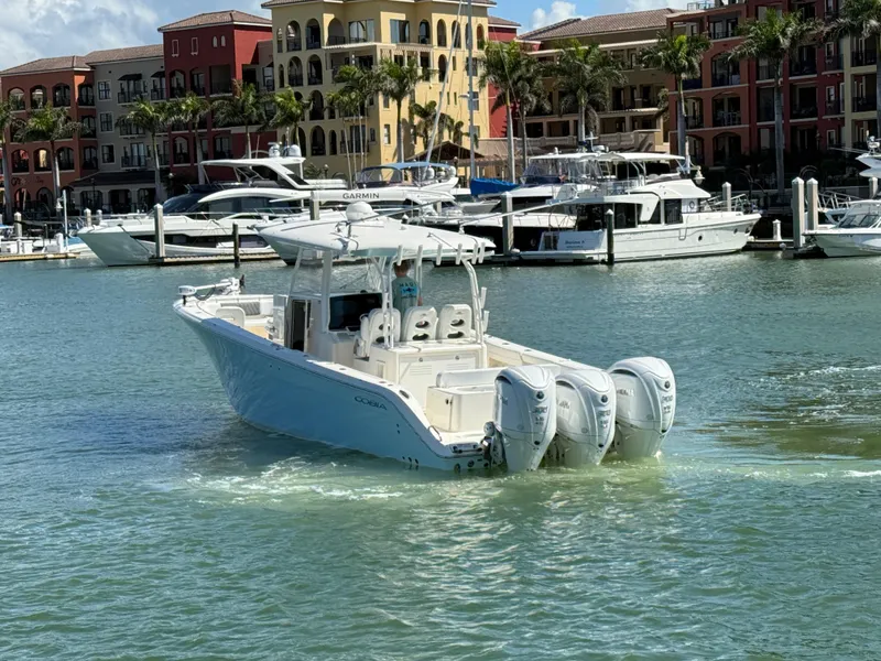 Slide: The Image of 2023 Cobia 350 Center Console boat cruising in a marina with colorful buildings. - 36