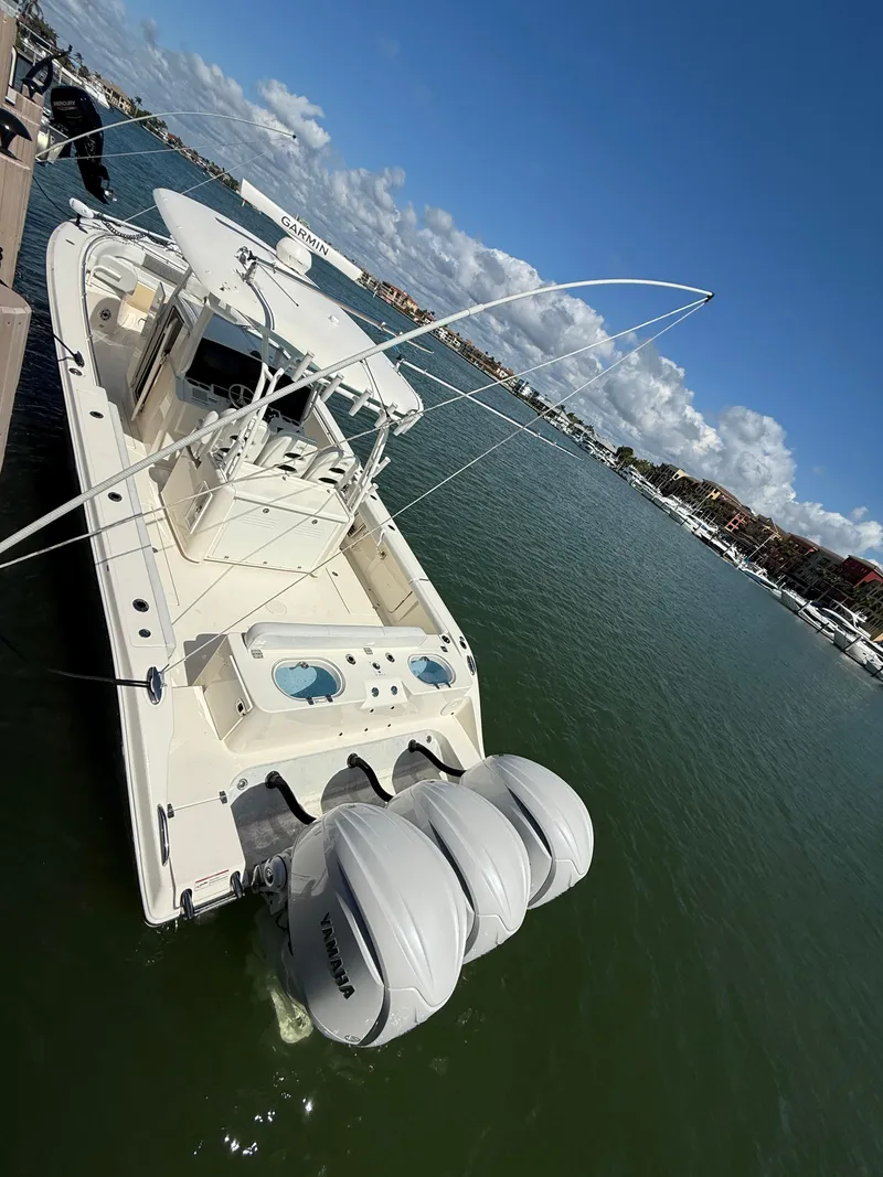 Slide: The Image of 2023 Cobia 350 Center Console boat docked with triple outboard engines. - 38