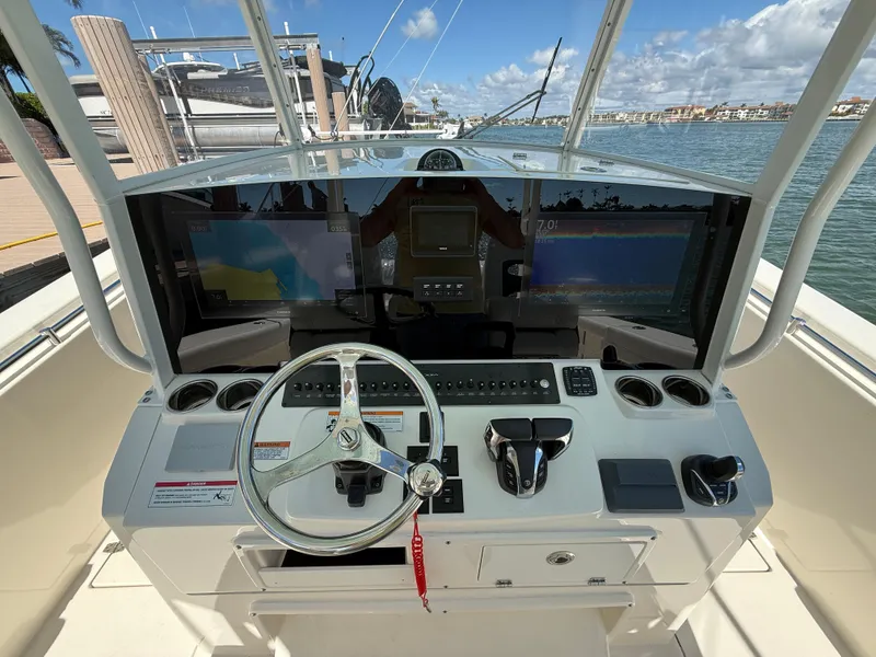 Slide: The Image of 2023 Cobia 350 Center Console helm with modern controls and dual displays, docked by the water. - 44