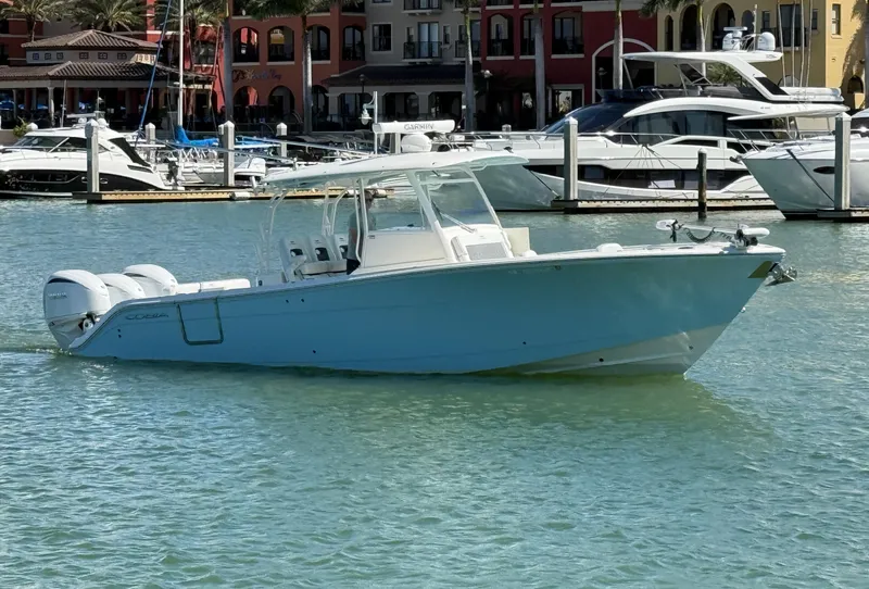 Slide: The Image of 2023 Cobia 350 Center Console boat docked in a marina with luxury yachts. - 5