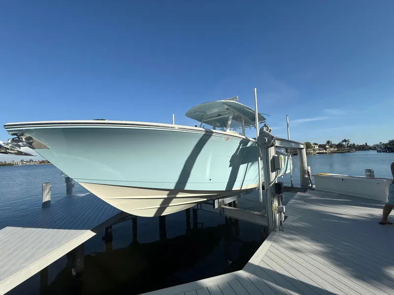 Slide: The Image of 2023 Cobia 350 Center Console boat on lift at dockside under clear blue sky. - 8