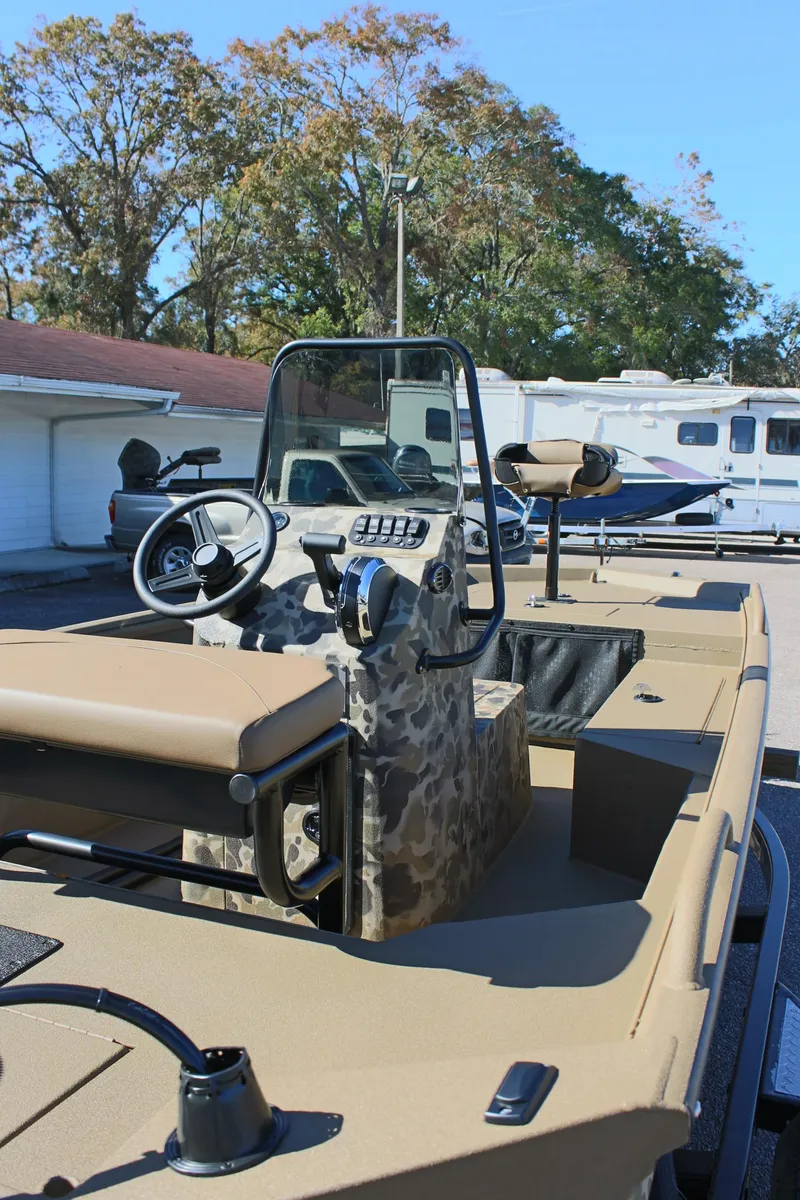 Slide: The Image of 2025 Excel 1860 F4 Shallow Water boat with camouflage interior, parked outdoors. - 10