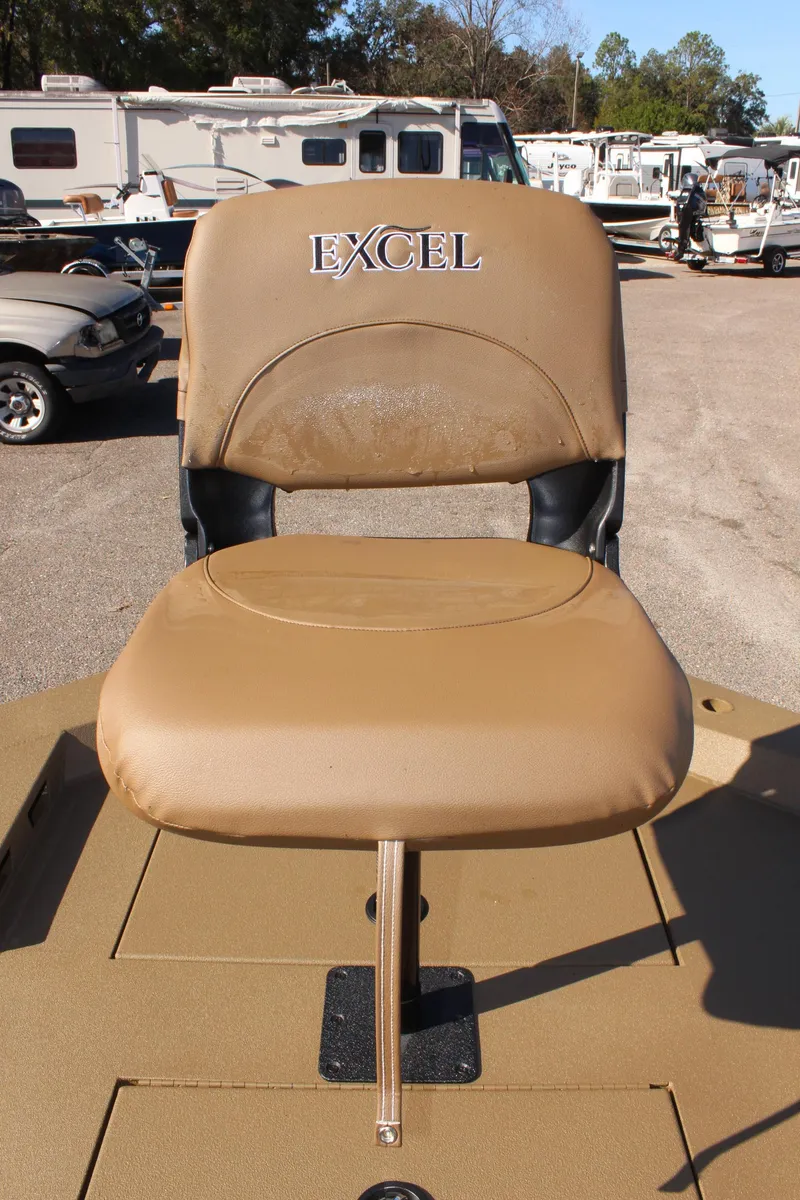 Slide: The Image of 2025 Excel 1860 F4 Shallow Water boat seat, tan color, outdoor setting. - 18