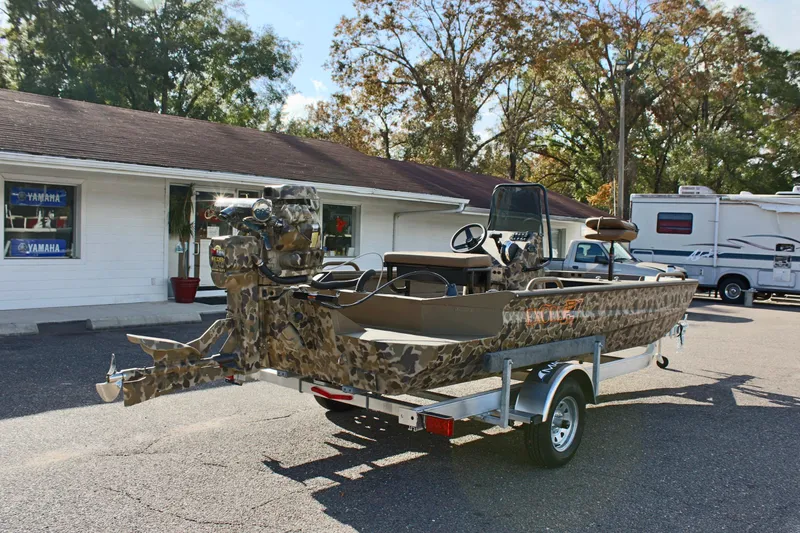 Slide: The Image of 2025 Excel 1860 F4 Shallow Water boat on trailer, camo design, parked outdoors. - 5