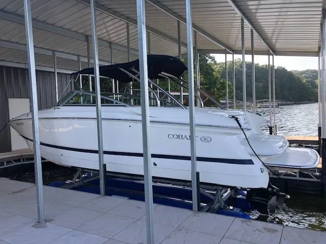 Slide: The Image of 2005 Cobalt 282 boat docked under a covered marina on a sunny day. - 2