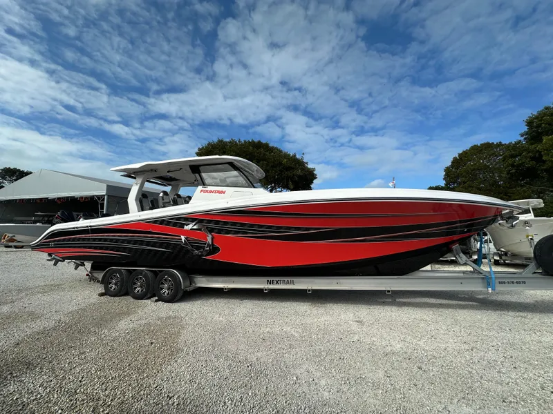 Slide: The Image of 2024 Fountain 43SCX boat with red and black design on a trailer, under a blue sky. - 1