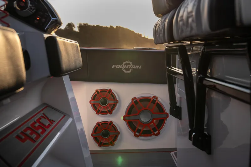 Slide: The Image of 2024 Fountain 43SCX boat interior with red speakers and logo, sunset in background. - 23