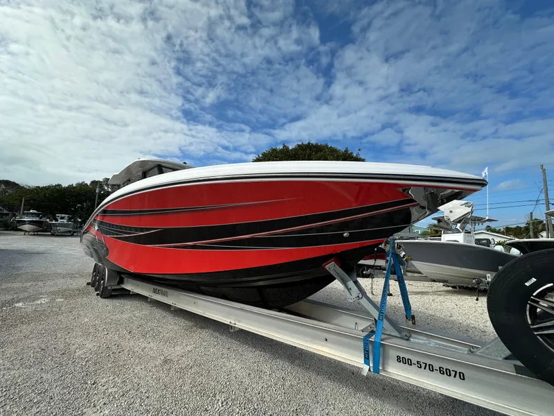 Slide: The Image of 2024 Fountain 43SCX speedboat with red and black design on a trailer under a blue sky. - 3