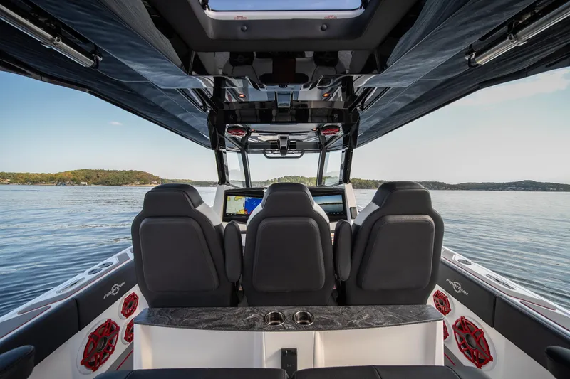 Slide: The Image of 2024 Fountain 43SCX boat interior with three seats, advanced dashboard, and scenic water view. - 42