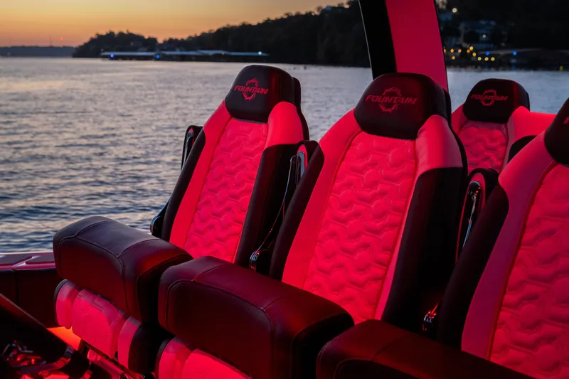 Slide: The Image of 2024 Fountain 43SCX boat seats illuminated by red lights at sunset on the water. - 70