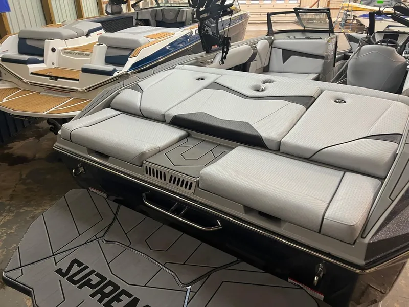 Slide: The Image of 2024 Supreme S220 boat with sleek gray seating and modern design in a showroom. - 11
