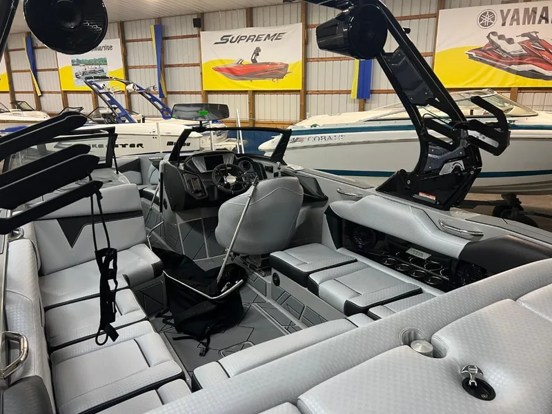 Slide: The Image of 2024 Supreme S220 boat interior with modern seating and steering, displayed in showroom. - 12