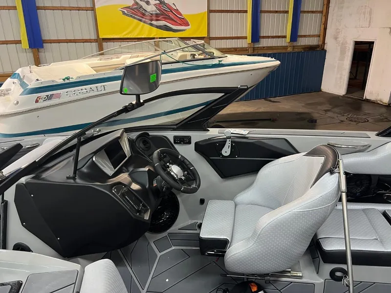 Slide: The Image of 2024 Supreme S220 boat interior with modern dashboard and seating in a showroom. - 16