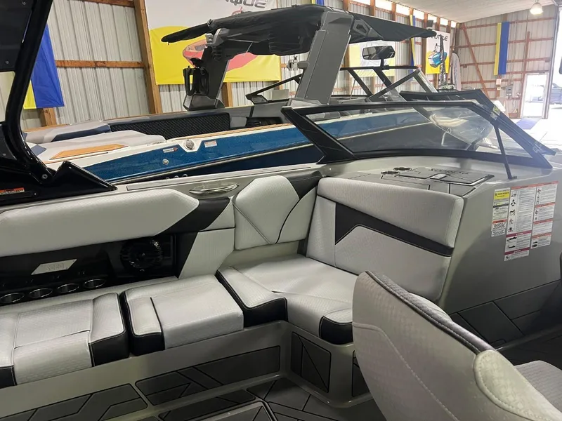 Slide: The Image of 2024 Supreme S220 boat interior with modern seating and dashboard in a showroom. - 28