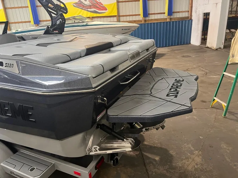 Slide: The Image of 2024 Supreme S220 boat in a garage, featuring a sleek swim platform. - 34