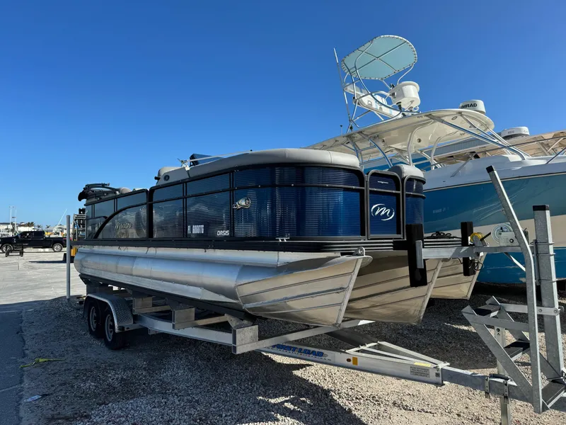 The Image of 2022 Manitou 23' Oasis RFSHP373 pontoon boat on trailer, parked outdoors. - 0
