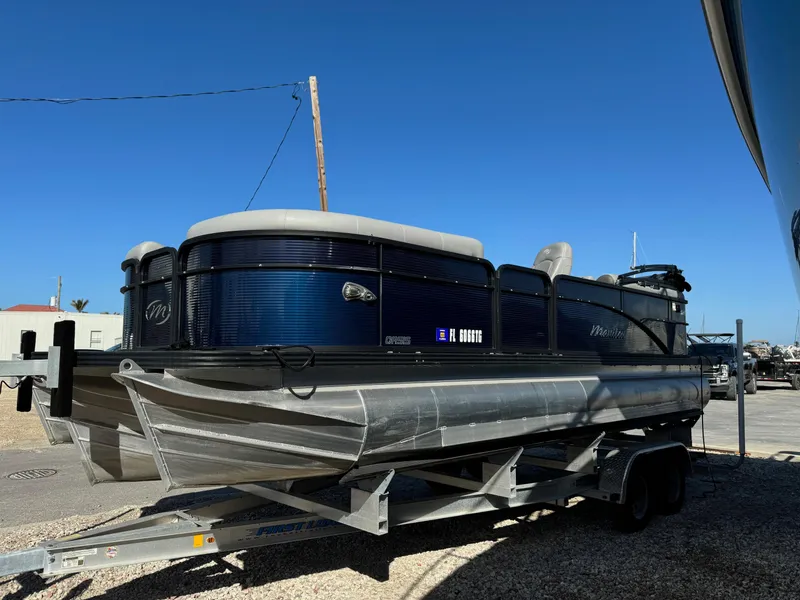 Slide: The Image of 2022 Manitou 23' Oasis RFSHP373 pontoon boat on trailer, parked outdoors. - 2