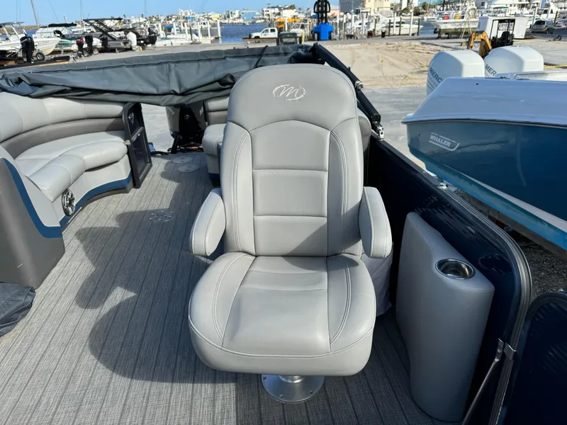 Slide: The Image of 2022 Manitou 23' Oasis RFSHP373 boat interior with gray captain's chair and seating. - 8
