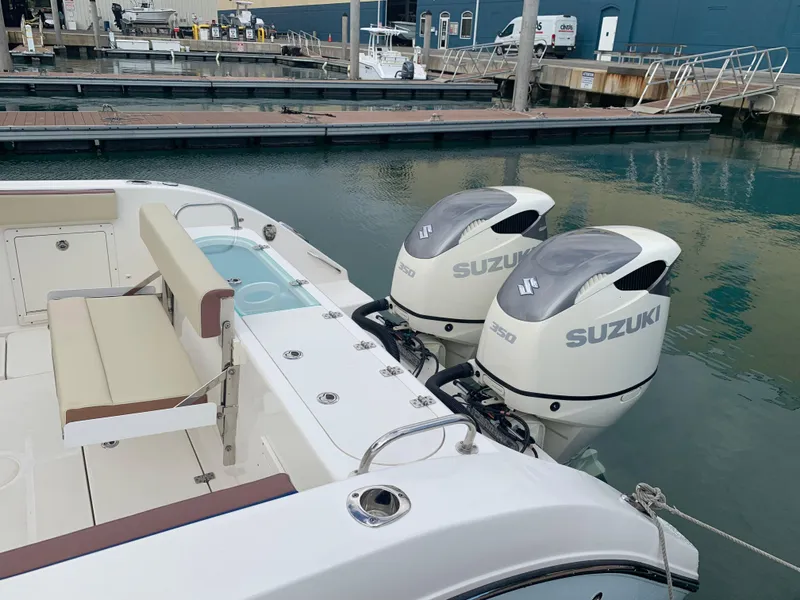 Slide: The Image of 2019 Century 3200 Center Console with twin Suzuki outboard motors at a marina. - 13