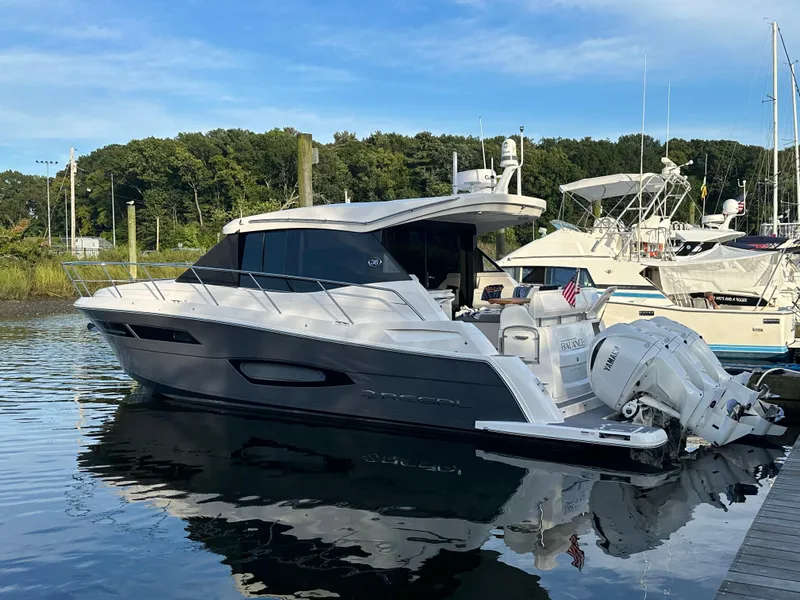 Slide: The Image of 2023 Regal 38 XO yacht docked in a serene marina setting. - 2