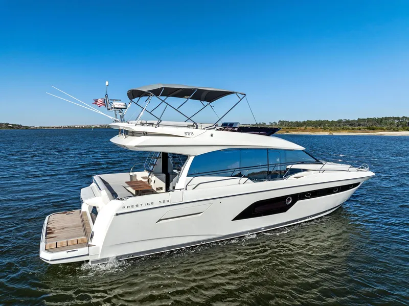 Slide: The Image of 2019 Prestige 520 Fly yacht cruising on open water under clear blue skies. - 1