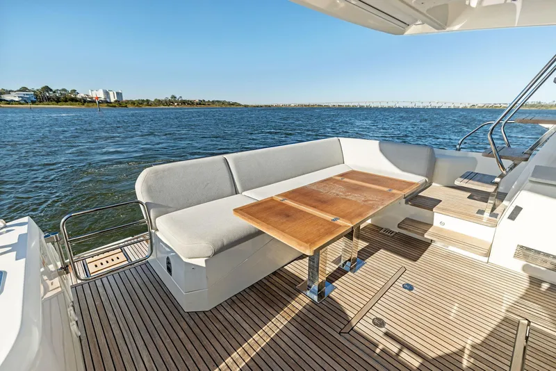 Slide: The Image of Prestige 520 Fly 2019 yacht deck with seating and table, overlooking serene water. - 15