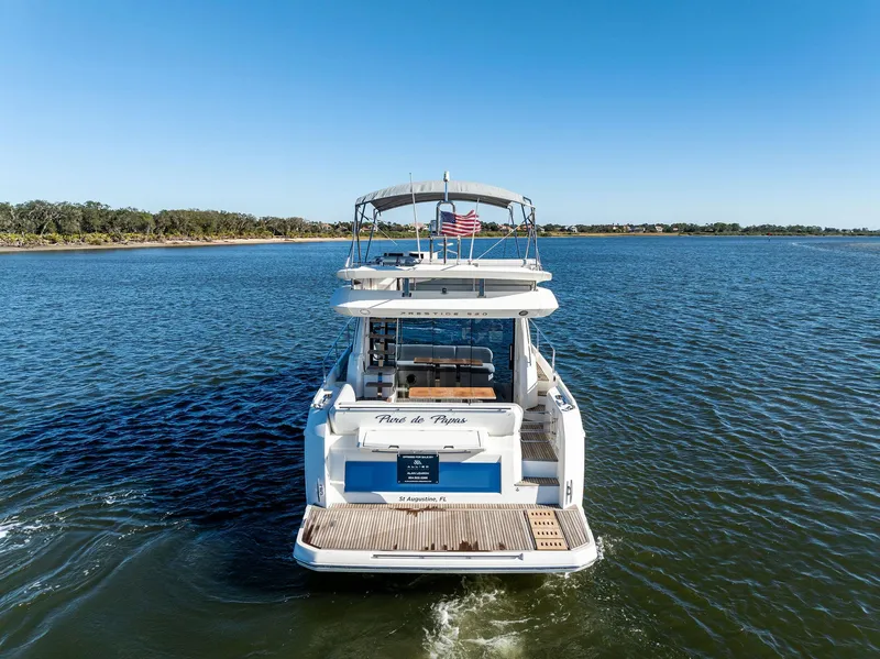 Slide: The Image of 2019 Prestige 520 Fly yacht cruising on a serene lake under a clear blue sky. - 2