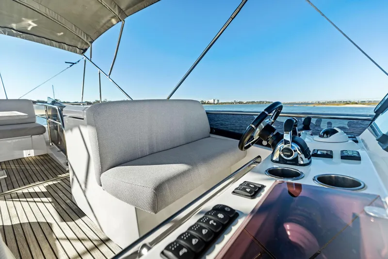 Slide: The Image of Prestige 520 Fly 2019 yacht helm with seating and controls, overlooking serene waters. - 28