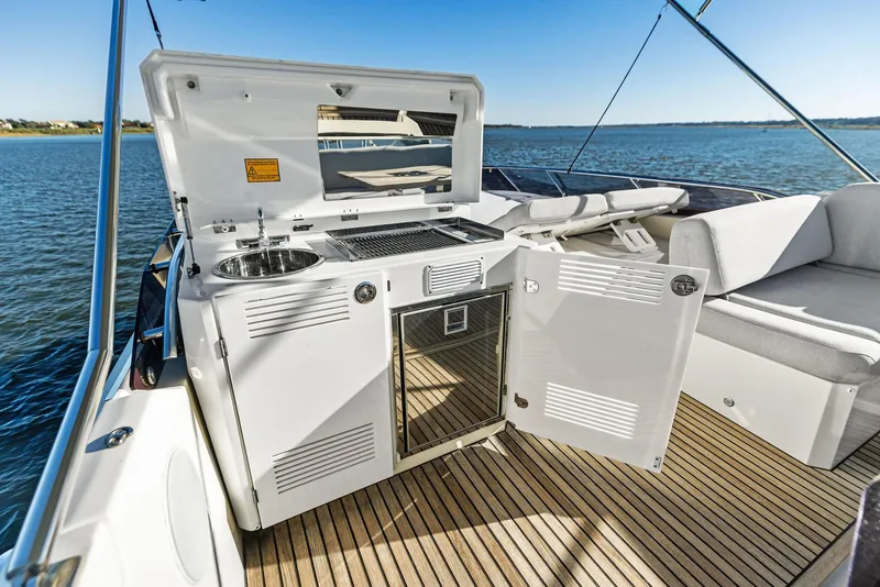 Slide: The Image of Prestige 520 Fly 2019 yacht with outdoor kitchen and seating area on deck. - 31