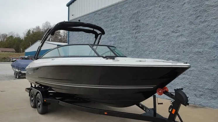 Slide: The Image of 2025 Monterey 224FS boat on trailer, black hull, parked outdoors. - 2