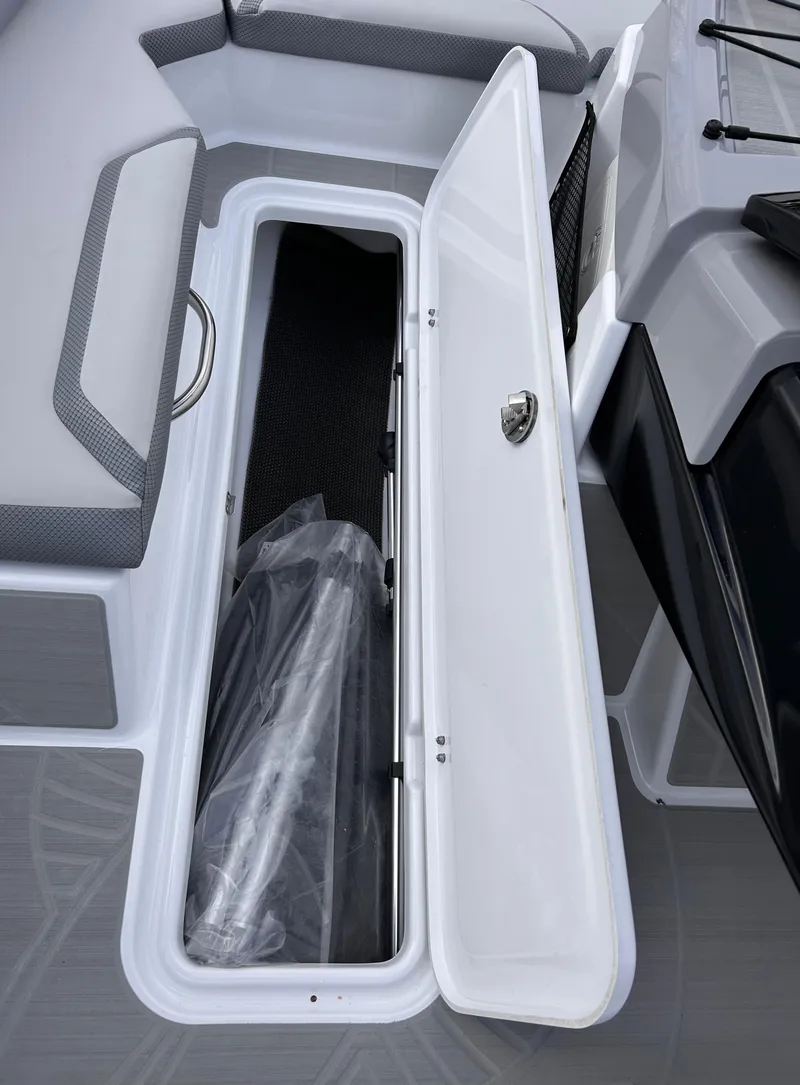 Slide: The Image of 2025 Scarab 165 SE boat storage compartment with open lid, showcasing interior space. - 34