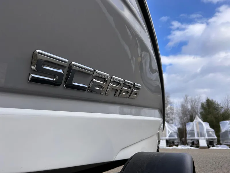 Slide: The Image of 2025 Scarab 165 SE boat with logo, parked outdoors under a cloudy sky. - 8
