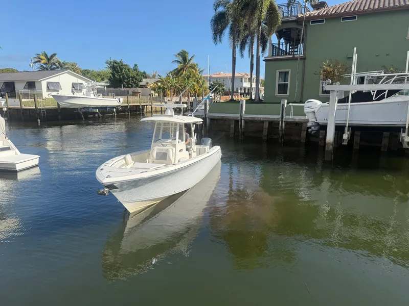 Slide: The Image of 2019 Cobia 301 Center Console boat docked in a sunny marina. - 0