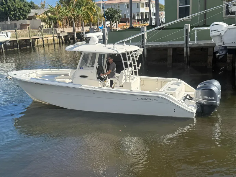Slide: The Image of 2019 Cobia 301 Center Console boat docked in a sunny marina. - 1