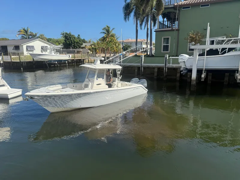 Slide: The Image of 2019 Cobia 301 Center Console boat docked in a sunny waterfront setting. - 2