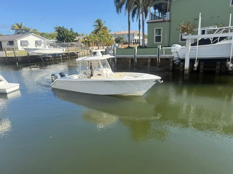 Slide: The Image of 2019 Cobia 301 Center Console boat docked in a sunny marina. - 3