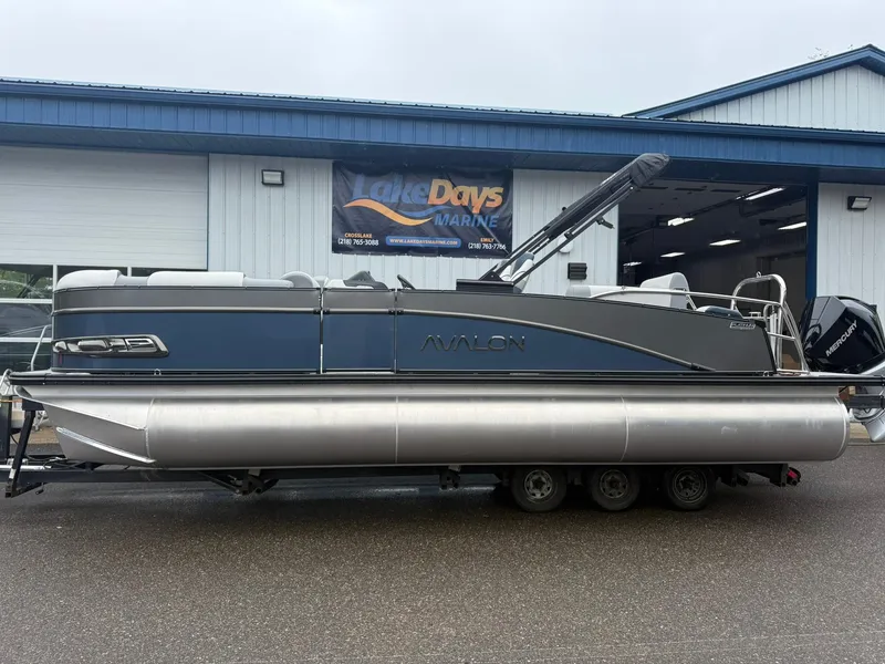 The Image of 2025 Avalon Catalina Quad Lounger Shift pontoon boat on trailer outside marine shop. - 1