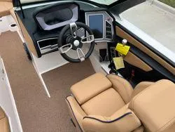 Slide: The Image of 2022 MasterCraft XT25 boat interior with modern steering and tan seating. - 13