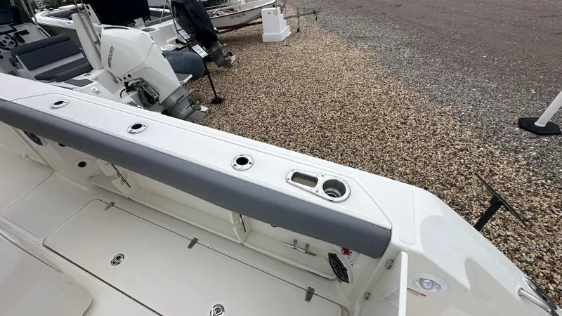 Slide: The Image of 2025 Boston Whaler 280 Outrage boat deck with seating and motor, on gravel surface. - 12