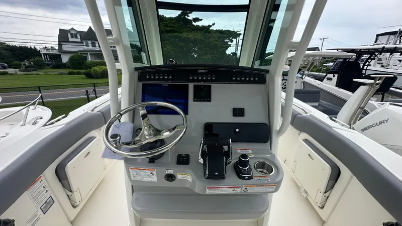 Slide: The Image of 2025 Boston Whaler 280 Outrage helm with steering wheel and control panel. - 23