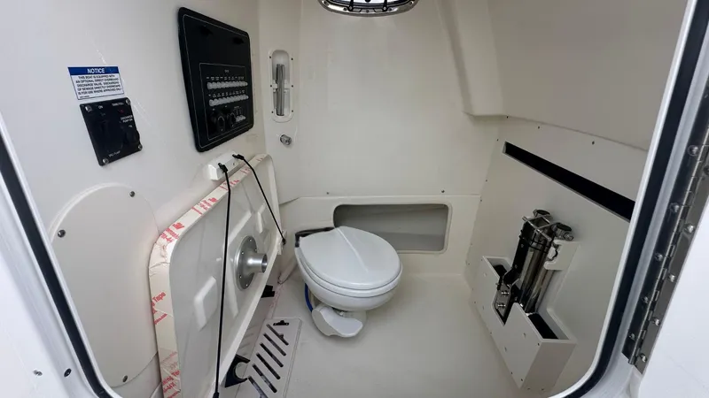 Slide: The Image of Interior of 2025 Boston Whaler 280 Outrage boat featuring a compact marine toilet. - 28
