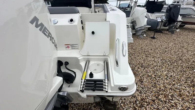 Slide: The Image of 2025 Boston Whaler 280 Outrage boat with Mercury engine, ladder, and sleek design on gravel. - 3