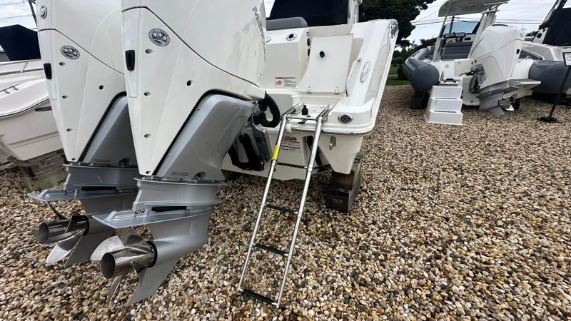 Slide: The Image of 2025 Boston Whaler 280 Outrage with dual engines and ladder on gravel surface. - 4