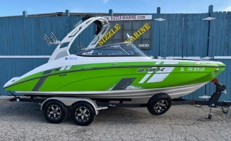 Slide: The Image of 2021 Yamaha Boats 212XE in vibrant green on a trailer, displayed at Sizzle Marine. - 0