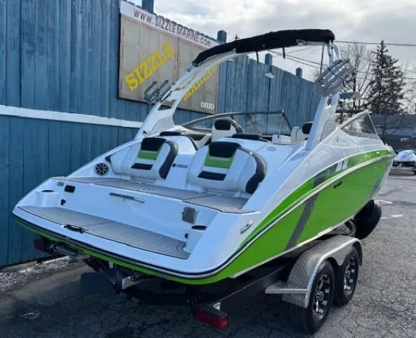 Slide: The Image of 2021 Yamaha Boats 212XE in green and white on a trailer, parked outdoors. - 3