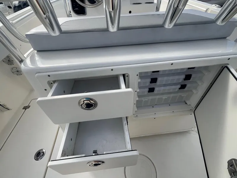 Slide: The Image of 2021 Cobia 237 Center Console boat storage compartments with open drawers and tackle storage. - 10