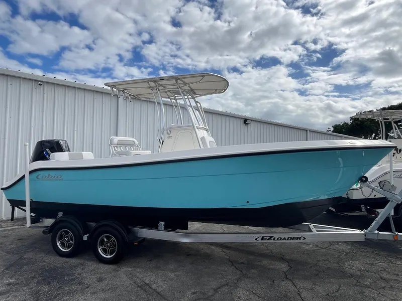 Slide: The Image of 2021 Cobia 237 Center Console boat on trailer, blue hull, parked outdoors. - 8